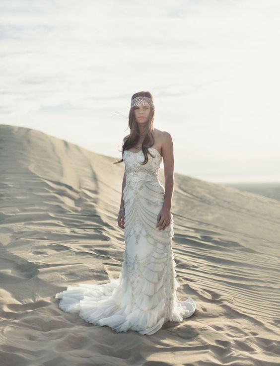 strapless embellished wedding dress with a train and a headpiece with rhinestones