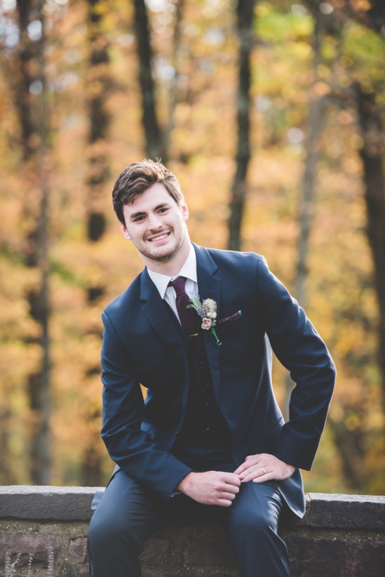 The groom in a navy suit, a white shirt and a burgundy tie