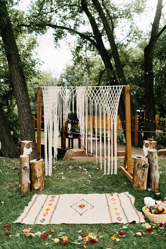 boho wedding arch with a macrame hanging, an embroidered rug and wooden logs