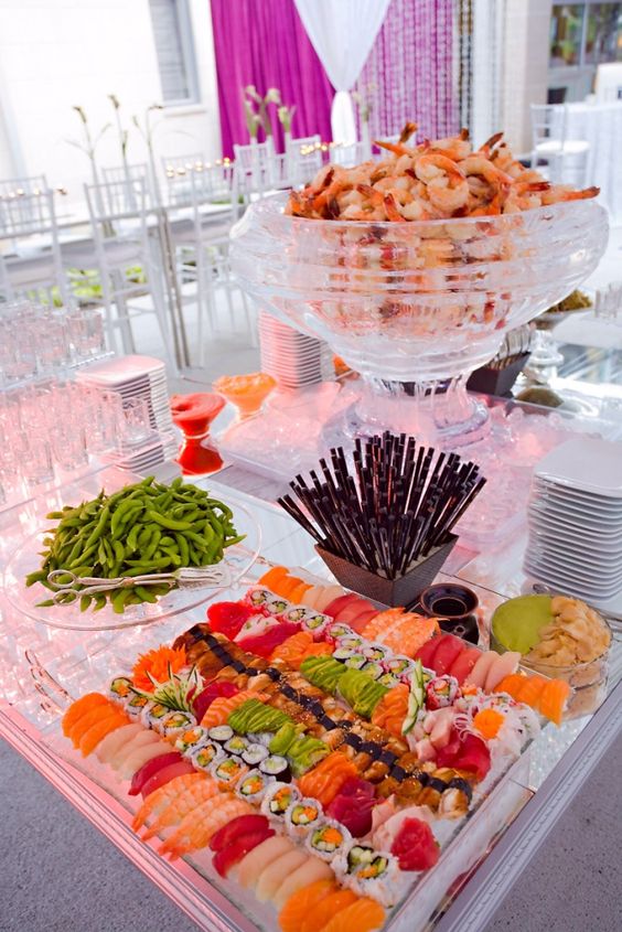sushi and rolls station on a glass tray and shrimps in a large glass bowl look very yummy
