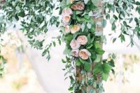 16 a wedding arch decorated with lush greenery and peachy flowers