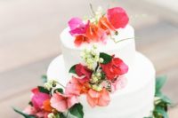 20 a white cake with bold tropical flowers and greenery