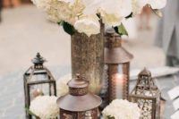 21 metal lanterns, candle holders and a large vase with white flowers