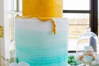 22 bold watercolor wedding cake in yellow and blue topped with white orchids and shells