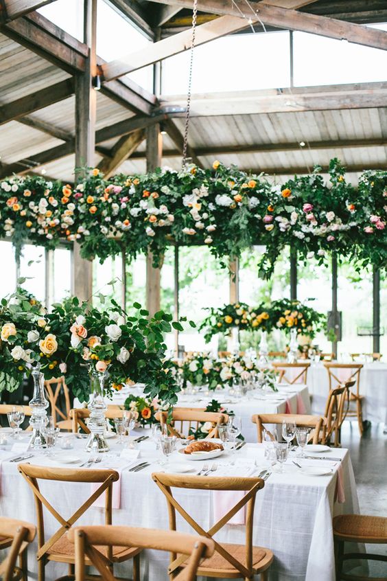 indoor summer wedding reception with lush flower decor over the tables