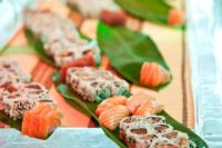 24 sushi and fish displayed on palm leaves are ideal for a tropical affair