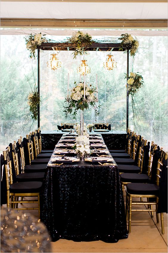 chic black and gold table setting with a sequin tablecloth and neutral florals