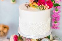 29 lace wedding cake topped with bold flowers and tropical fruits on display