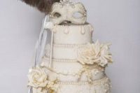 32 a lush ivory wedding cake with sugar roses and a mask