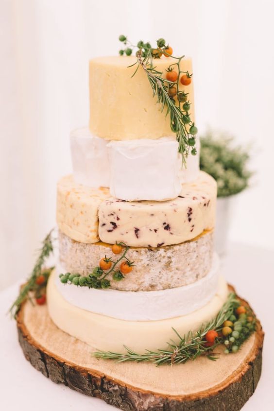 cheese tower displayed ona  wood slice with rosemary and small tomatoes