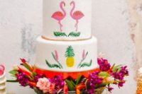 32 wedding cake topped with flowers and with flamingos and pineapple decor