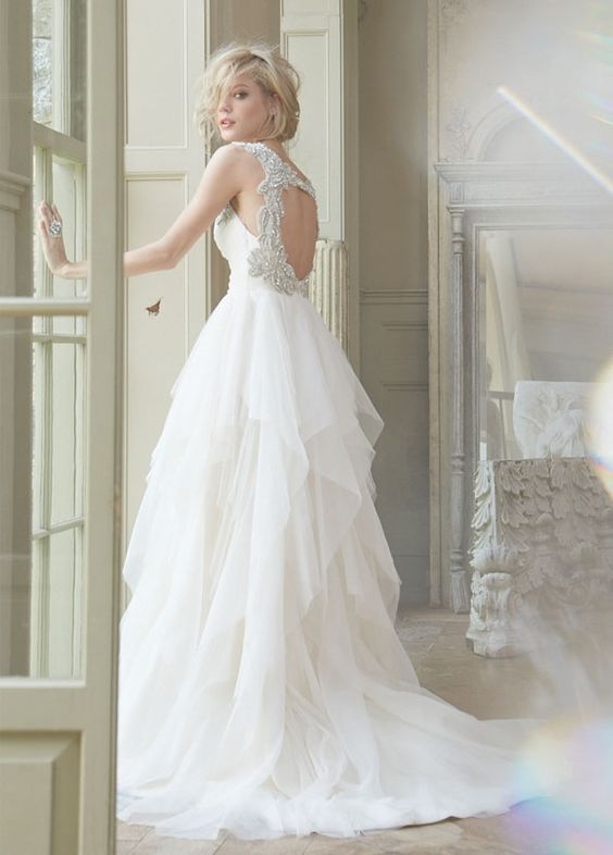wedding dress with a heavily embellished circle cutout back and a draped tulel skirt