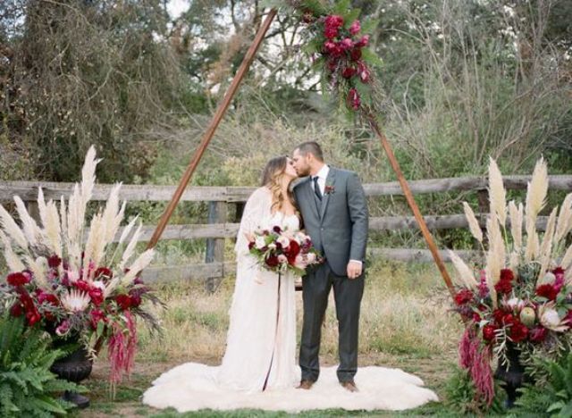 triangle wedding arch with bold flowers and pampas grass on the sides