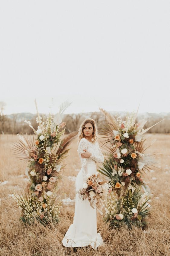a boho fall wedding altar with greenery, leaves, fronds and white, peachy and rust blooms is a cool idea for a fall wedding