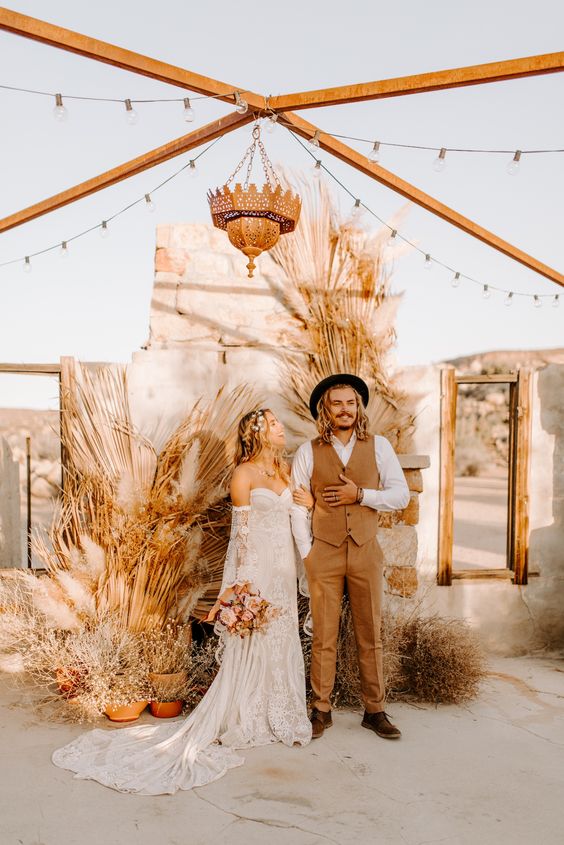 a boho wedding backdrop composed of fronds and dried grasses in pots is a cool solution for a neutral boho wedding