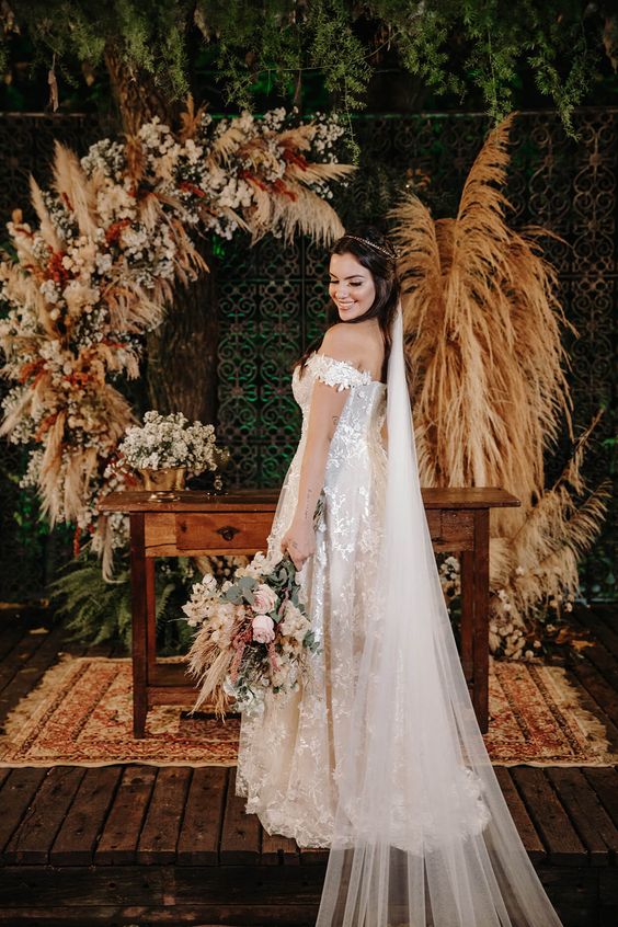 a boho wedding backdrop of pampas grass, pink, white and red blooms is a cool idea fro a boho wedding