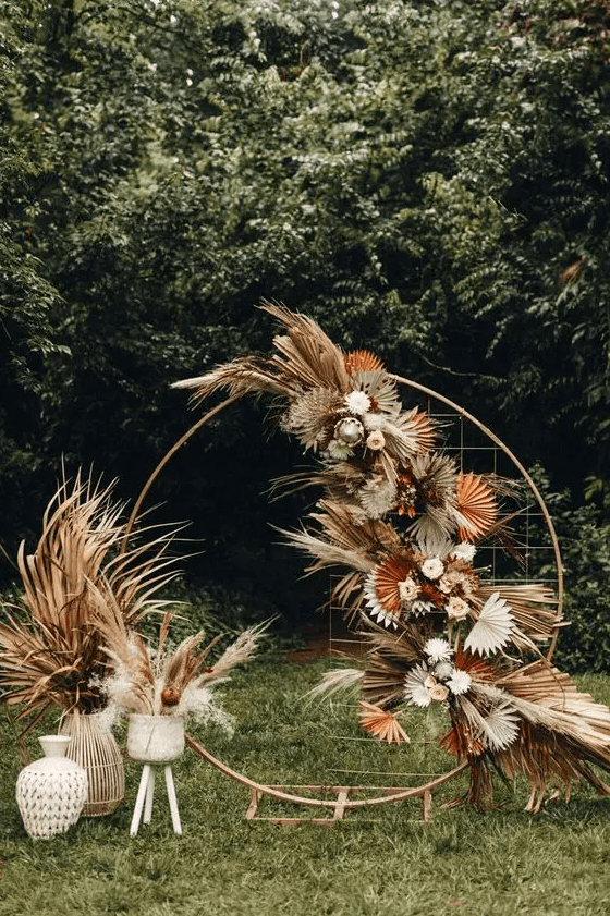 a boho wedding backdrop with fronds, pampas grass, blush and white blooms and some greenery
