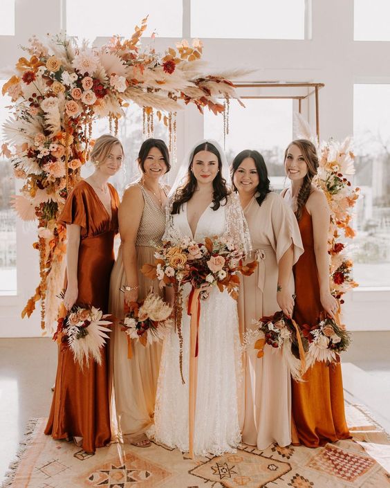 A bright fall boho wedding arch with pink, peachy and white blooms, fronds and pampas grass is drop dead gorgeous