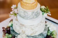 a cheese tower with fresh grapes all over and some blooms
