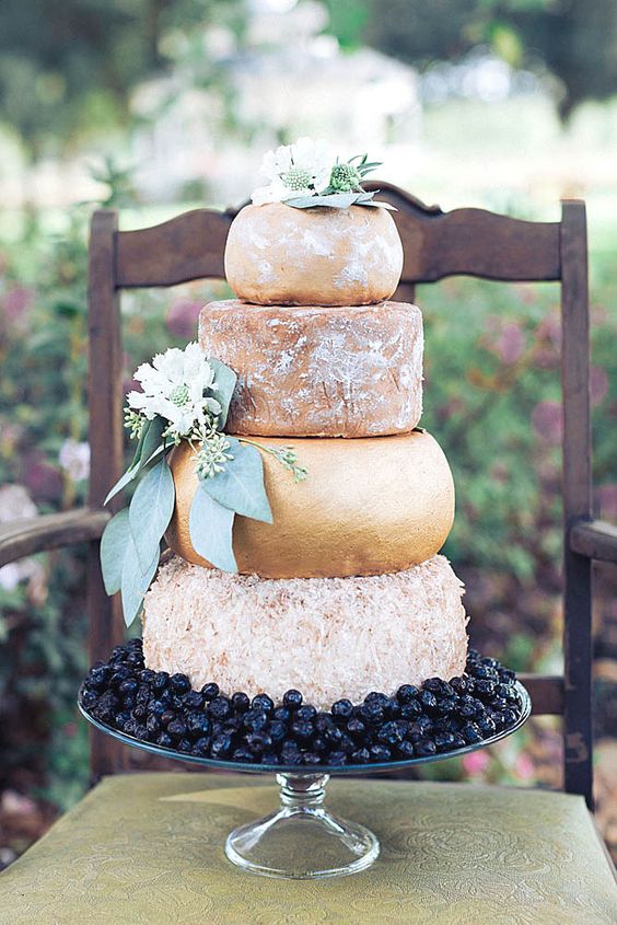 a huge cheese tower with greenery and flowers and some cherries for displaying