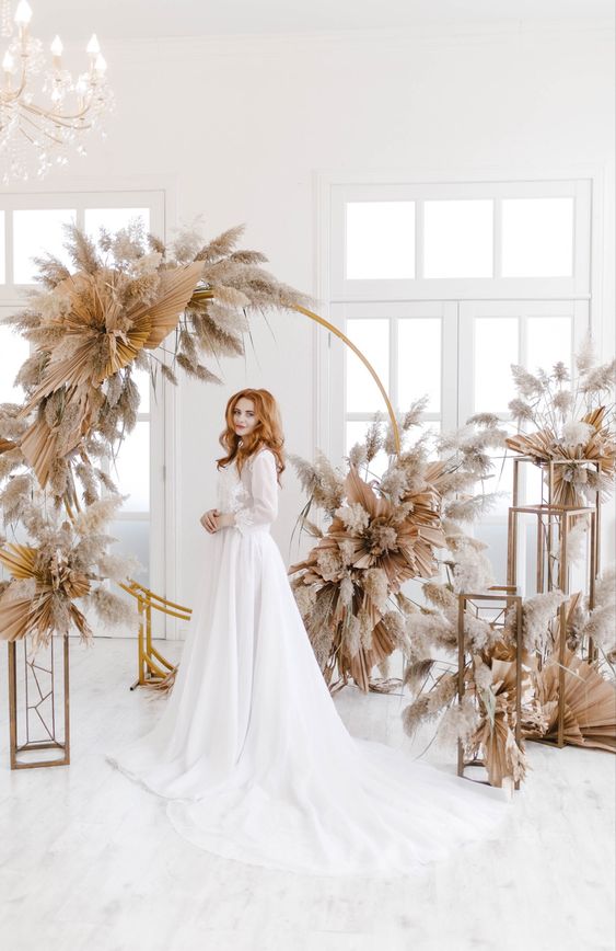 a lovely round wedding arch covered with fronds and pampas grass and some arrangements around is amazing for a boho wedding