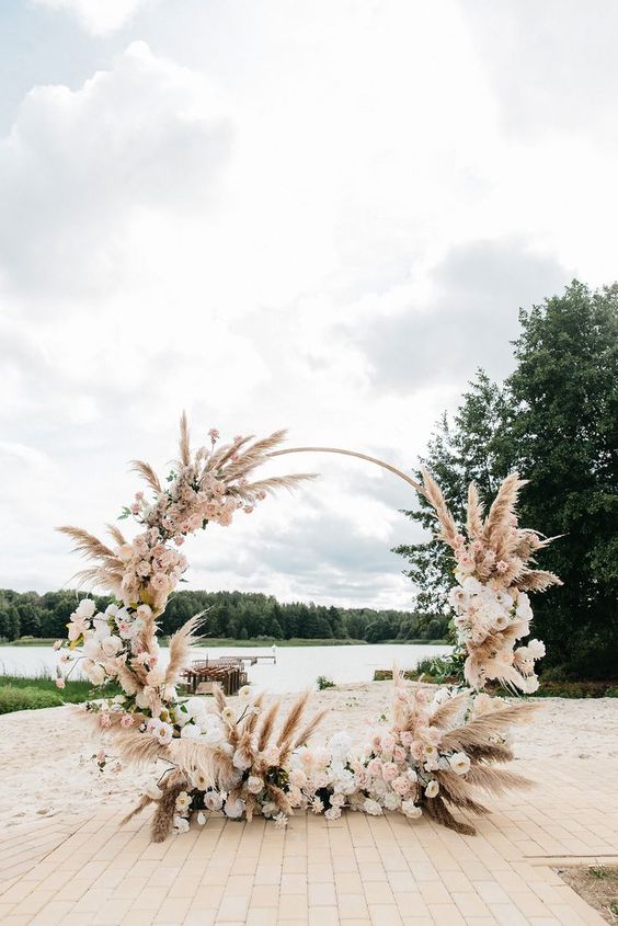 a refined boho tropical wedding altar with pampas grass, pink and blush blooms is a gorgeous idea for a tropical beach wedding