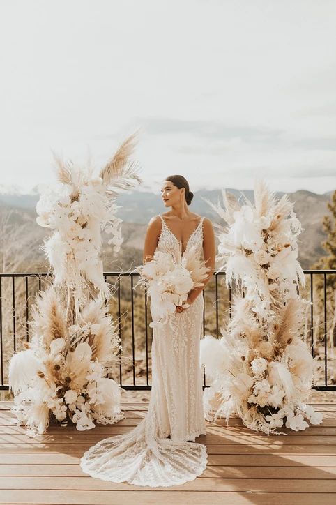 a refined white boho wedding altar with orchids, pampas grass, roses and fronds is a gorgeous idea for an exquisite wedding