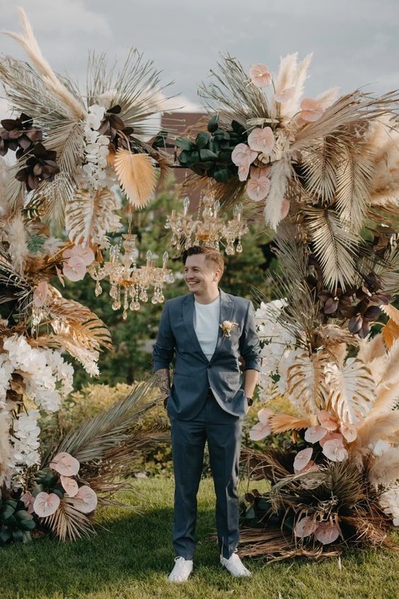 a super lush boho wedding arch covered with foliage, pink anthuriums, white orchids, fronds is amazing for a tropical boho wedding
