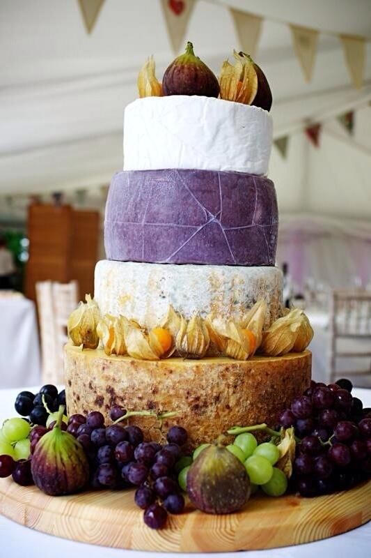 bold cheese tower with grapes and figs on a wooden stand