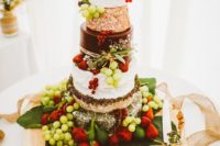 cheese wheel cake with fresh grapes, strawberries placed on a palm leaf