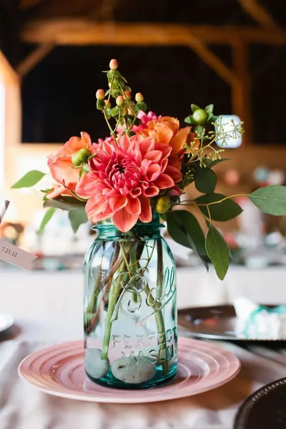 a blue mason jar with a colorful floral arrangement for a summer or fall wedding that you can DIY
