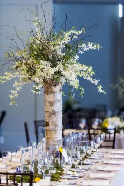 a tall vase wrapped with birch bark and with flowers on branches