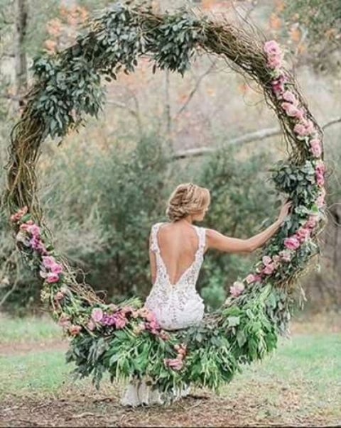 oversized wedding wreath with pink blooms can be used as a swing for the bride