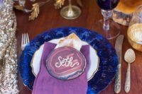 07 The wedding table setting was deccorated with bold blue plates, purple glasses and of course stone slices