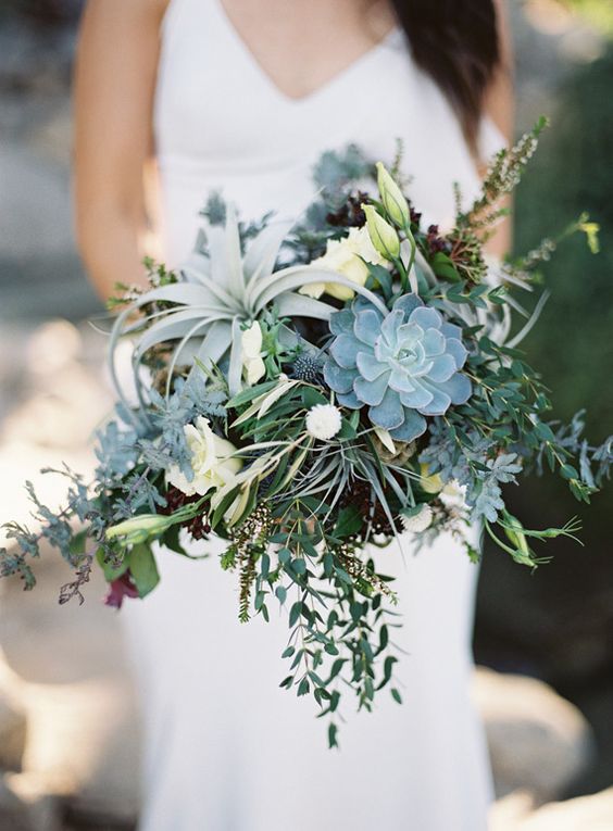 a lush messy bouquet with succulents, air plants, greenery and some blooms