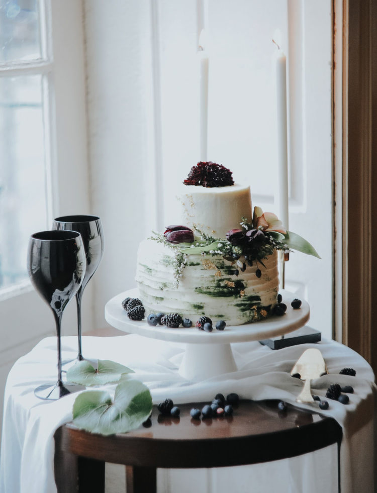 The textural wedding cake was topped with leaves, berries and dark purple blooms