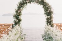 13 messy wedding arch covered with greenery, white and pink blooms and the aisle lined with white flowers