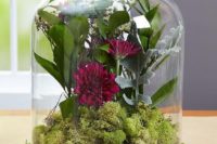 16 a rustic centerpiece with a wood slice, moss and dark flowers