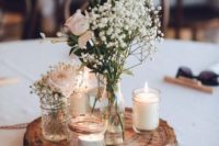 16 a wooden slice with candles and a floral centerpiece of roses and baby’s breath