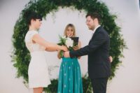 18 a giant greenery wreath as a backdrop for a modern urban ceremony