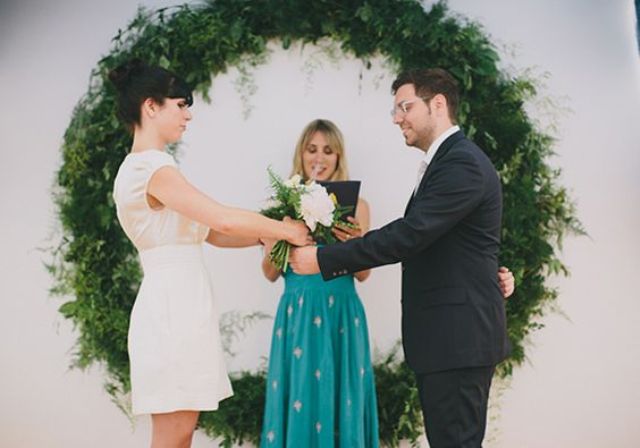 a giant greenery wreath as a backdrop for a modern urban ceremony
