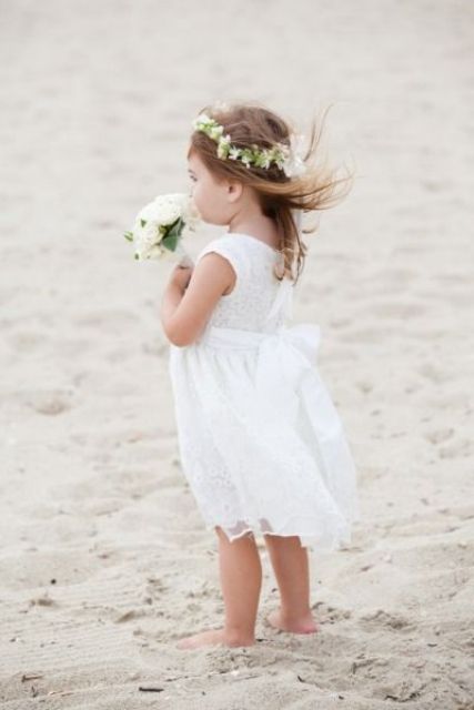 a white lace sleeveless dress and a white floral crown