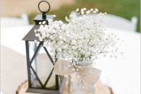 25 a wood slice with a mason jar with baby’s breath and a lantern