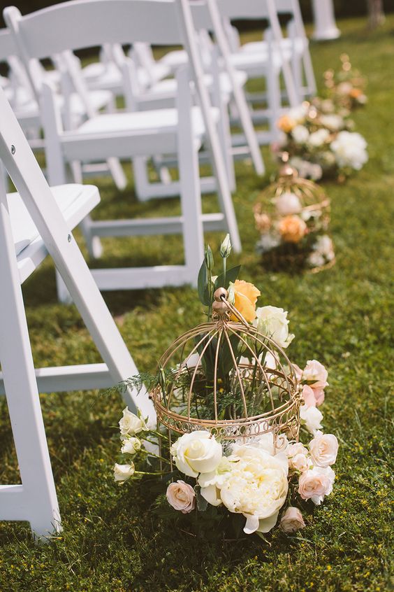 vintage birdcages line the aisle and were filled with flowers for a romantic look