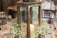28 a rustic lantern of wood, candles around and vintage vases with baby’s breath