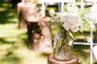 28 log stands with greenery and neutral flowers for a rustic summer aisle