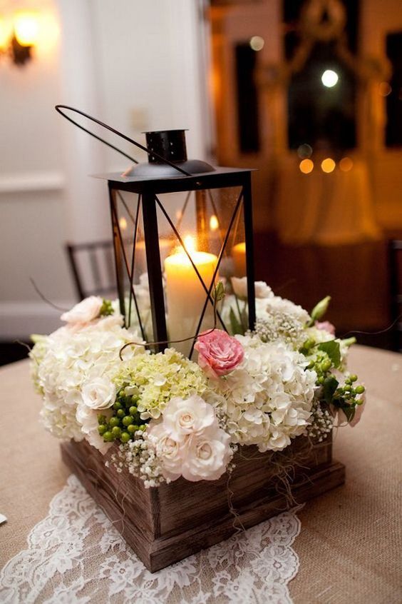 une boîte en bois avec des fleurs fraîches et une lanterne à bougie noire