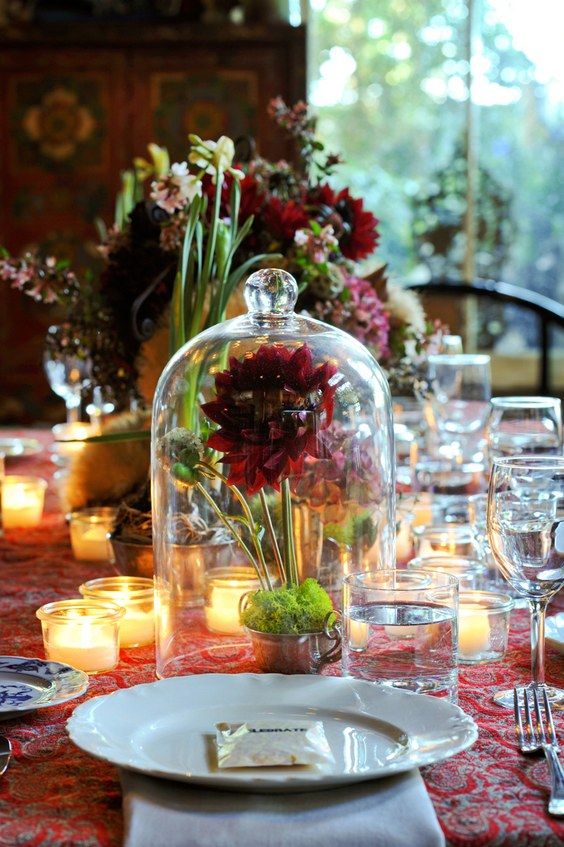 a bold wedding centerpiece of a cloche with burgundy blooms and moss inside is a super cool idea