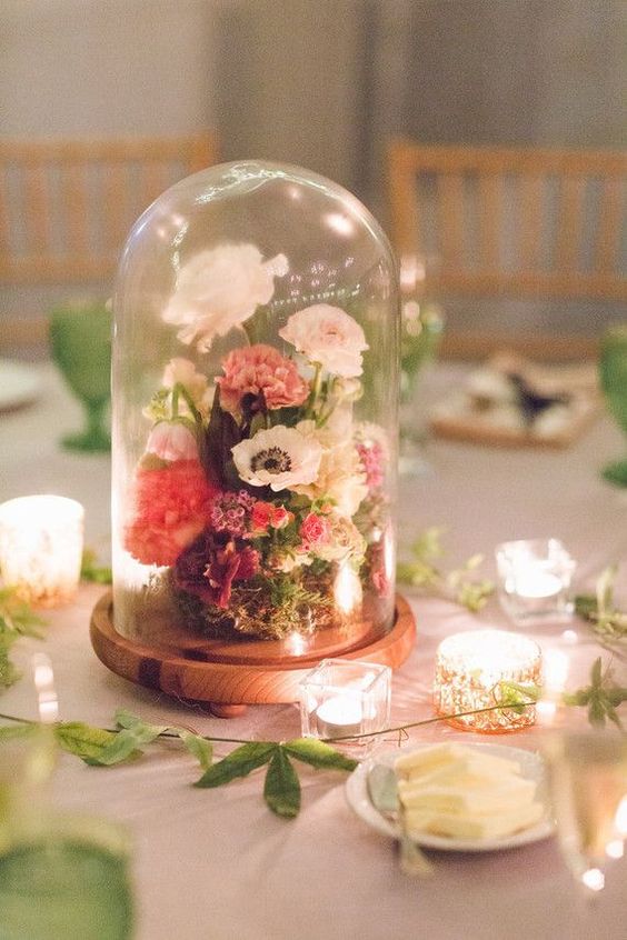 a catchy floral wedding centerpiece of a cloche with pink and white blooms and greenery
