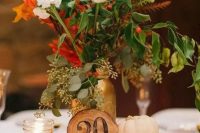 a chic fall wedding centerpiece of a wood slice, pumpkins, candles and blush and white blooms and fall foliage